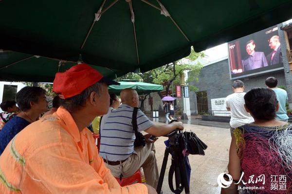 户外的大屏幕也在直播阅兵盛况,人们停下脚步看直播。