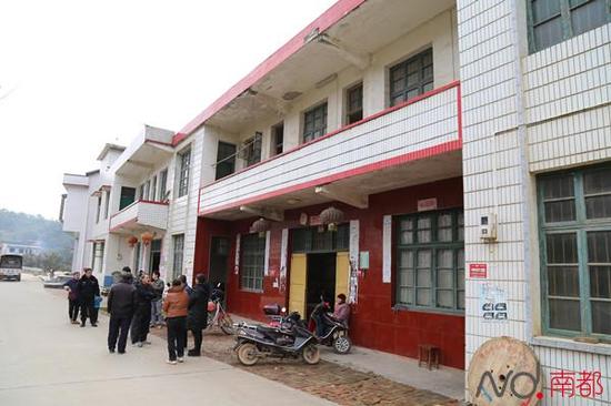 犯罪嫌疑人聂露勇的老家,村民在门口围观。门前,默默静坐的是他86岁的老奶奶。