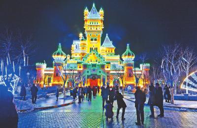 游客在灯光映衬下的方特城堡前拍照留念。